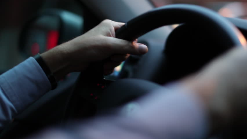 Closeup of person hands on steering wheel driving car. Man driving a vehicle. Slow-motion 120fps driving commuting from work