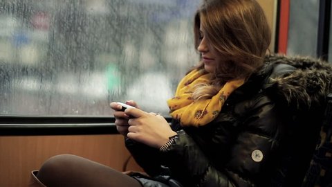 Young woman using smartphone while riding tram, steadicam shot
