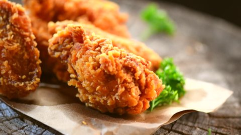 Crispy fried chicken wings and legs on a wooden table rotation 360 degrees. Breaded delicious fried chicken tasty dinner. 4K UHD video footage. Ultra high definition 3840X2160