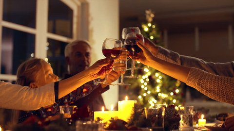 Family toasting wine at christmas dinner. Family enjoying christmas dinner together at home, with focus on hands and wine glasses.
