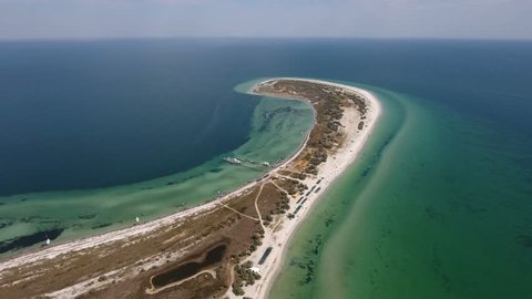 A stunning bird`s eye view of a curvy seacoast of Dzharylhach island in the Black Sea in summer. It is covered with white sand and multicolored weeds and wetland. The skyscape is surrealistic