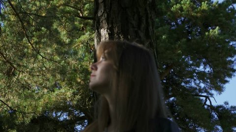A beautiful girl wanders through the forest. The girl was lost. In the background, the sky.