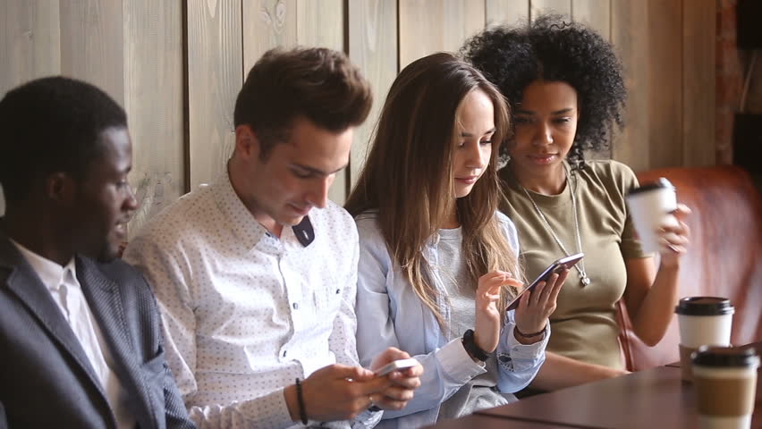 Multiracial friends relaxing on coffeehouse couch, four diverse young men and women using smartphones and talking, multi-ethnic phone addicts obsessed with cells at meeting in cafe, mobile addiction Royalty-Free Stock Footage #32241913