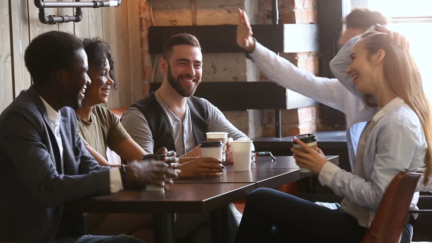 Multi-ethnic friends laughing having fun at meeting in coffeehouse, african and caucasian male buddies giving high five after telling good funny joke, multiracial young people hanging out in cozy bar Royalty-Free Stock Footage #32241934