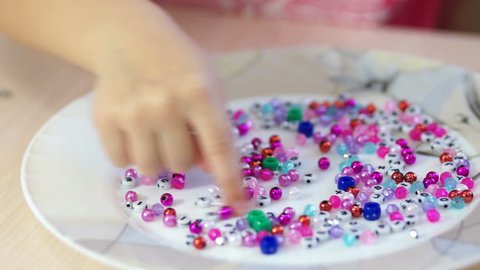 Child preparing beads for jewelry