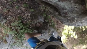  a younger man climbs to the rock, a clip from his perspective