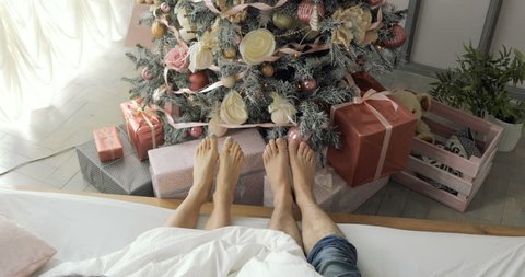 Couple Feet across from the Christmas tree, Man and Woman relax their feet. Close up. Winter and Christmas holidays concept.