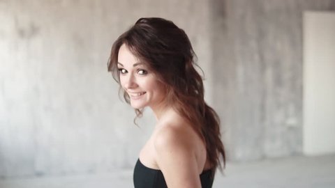 cheerful carefree girl turns on the camera and smiles gently. portrait of a young woman in a black dress. a girl with smoky eyes. slow motion