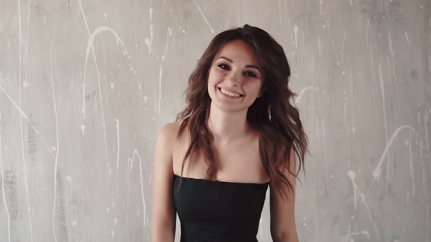 charming girl in black dress smiles and goes to the camera. young woman with evening make-up. slow motion