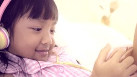 Asian girl wearing headphones Watching happy video clips, lifestyle Children's digital age