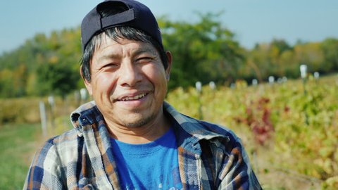 Portrait of a Mexican working farmer. Standing on the field, looking at the camera, smiling