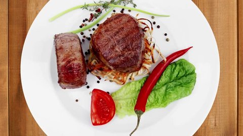 grilled beef fillet with thyme red hot chili pepper and tomato on plate  over wooden table