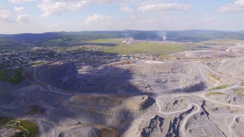 Aerial view industrial of opencast mining quarry with lots of machinery at work - view from above. Extraction of magnesite