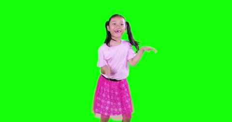 Happy toothless little girl with pigtail hair, dancing in the studio while chewing gum. Shot in 4k resolution with green screen background