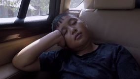 Video footage of a cute little boy sleeping inside car while leaning on his hand
