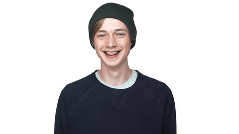 slowmotion portrait of happy teenage boy in braces wearing hat laughing smiling on camera isolated over white background closeup. Concept of emotions