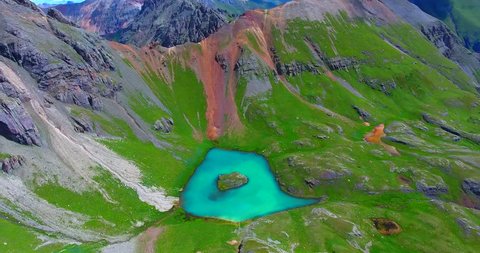 Rocky Mountain Ridgeline With Blue Island Lake Below Green Cliffs - Aerial Approaching Fly-Over - Colorado, USA
