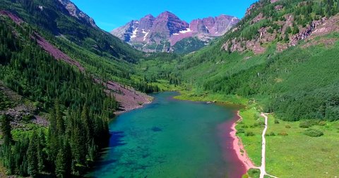 Mountain Lake With Purple Peaks In Green Valley - Approaching Aerial View - Maroon Bells, Colorado, USA