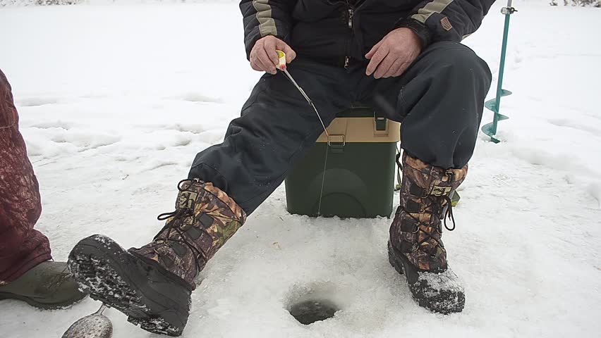 Man is fishing with fishing rod on winter fishing.