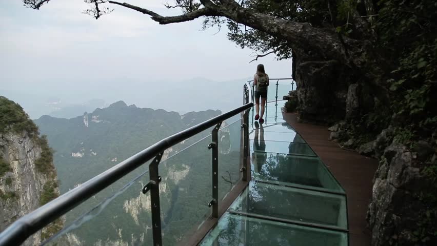 Tourists carefully walk over a glass bridge on Tian Shan National Park in Hunan province, China