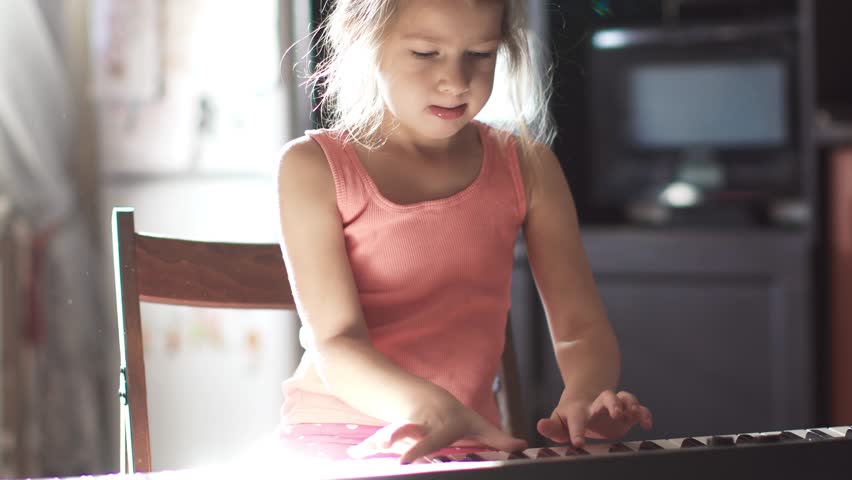 6 year old child learns to play the piano. little cute little girl is playing a synthesizer at home Royalty-Free Stock Footage #32286145