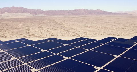 Aerial view flying over large industrial solar energy farm in desert