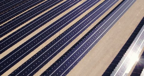 Aerial shot flying over rows of solar panels on a solar farm in desert 