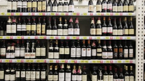 a lot of wine on the shelves in the supermarket. Alcoholic shop. travel by camera on bottles of wine