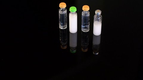 Four vials of insulin on a black background. Four ampoules for injection on a black background, close-up.