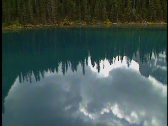 Low level flight over lake and trees to reveal Lake Gloria in Banff National