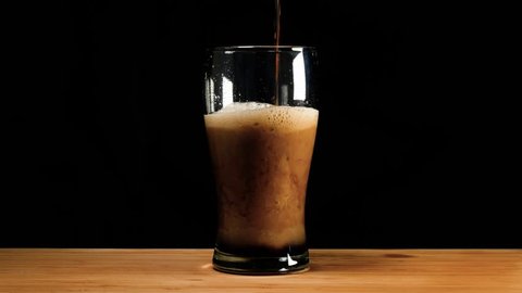 A pint of dark ale beer or stout is poured up.