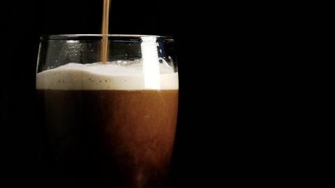  Delicious hand crafted stout, porter or dark beer is poured into a glass