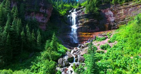 Smooth Panning Shot Of Bear Creek Waterfall, Colorado, USA - Red Cliffs With Green Pine In Canyon