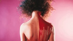 On the back of a curly model pours a red paint