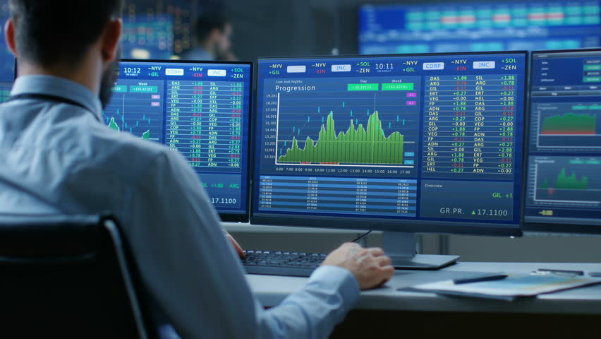 Over the Shoulder View of Stock Market Trader Working on a Computer with Multiple Monitors Showing Stock Ticker Numbers and Graphs. Shot on RED EPIC-W 8K Helium Cinema Camera. Royalty-Free Stock Footage #32305273