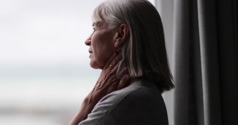 Senior woman looking out of window thinking