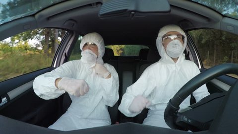 Cheering scientists in hazmat suit dancing and having fun at work in car while driving to contagious field