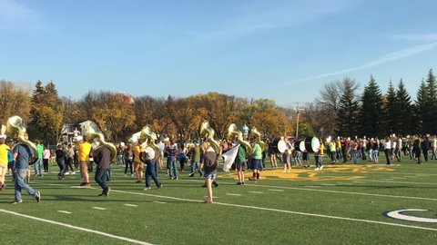 FARGO, ND - OCTOBER 20, 2017:  Marching band rehearses under bright angled late afternoon sunshine on football field before event.  