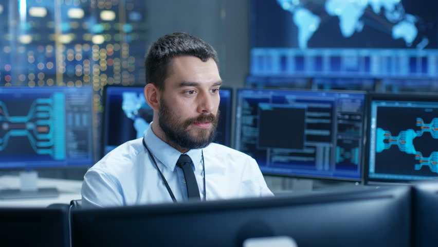 In the System Control Center Operator Working Surrounded by Displays Showing Relevant Data. In the Background Data with Interactive Map. Shot on RED EPIC-W 8K Helium Cinema Camera. | Shutterstock HD Video #32307787