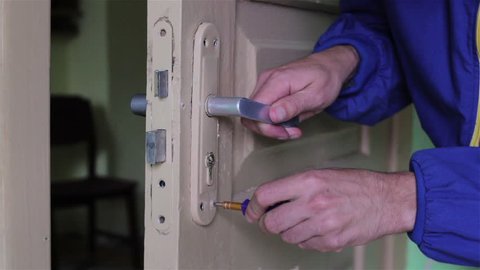 Worker Setting The Door Lock/The man repairs the door lock in the room