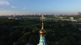 4K high quality aerial video scenic view of beautiful light blue church overlooking green park, distant city and hills in Krylatskoye area on quiet late afternoon near Moscow River in Moscow, Russia