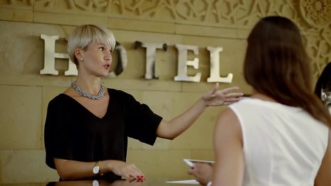 hotel manager is explaining client a rules of the hotel, showing by hands directions of main places