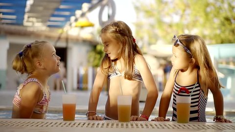 funny little girl is speaking her friends comical story,laughing together, standing in swimming pool