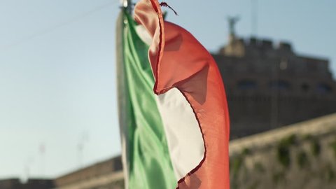 Slow motion of Italian flag waving ahead Castel Sant’Angelo castel in Rome, Italy, during sailing on the river Tiber. Italian symbols in European and Italian holidays.