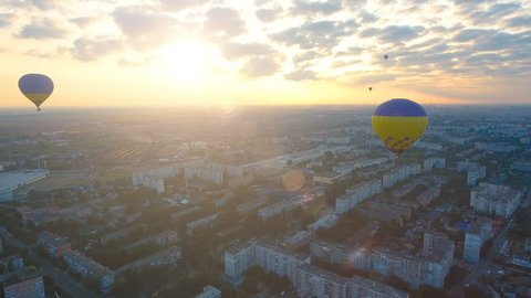 Couple of hot air balloons floating over city against rising sun, early flights Stockvideó