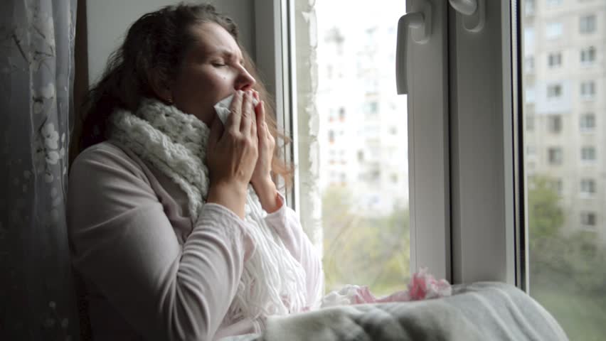 A woman is sick with flu, a cold coughs, sitting by the window. | Shutterstock HD Video #32339383