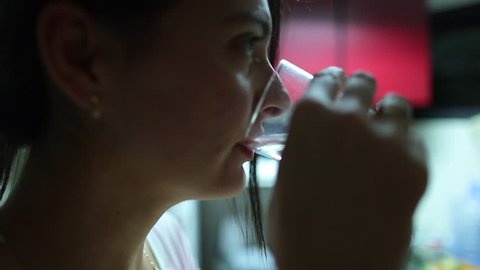 Woman drinking water in slow-motion. Candid moment of woman in her 30s drinking water