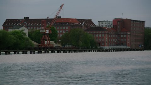 May, 2017 Berlin, Germany. Spree river with old crane and brick buildings on a cloudy day.