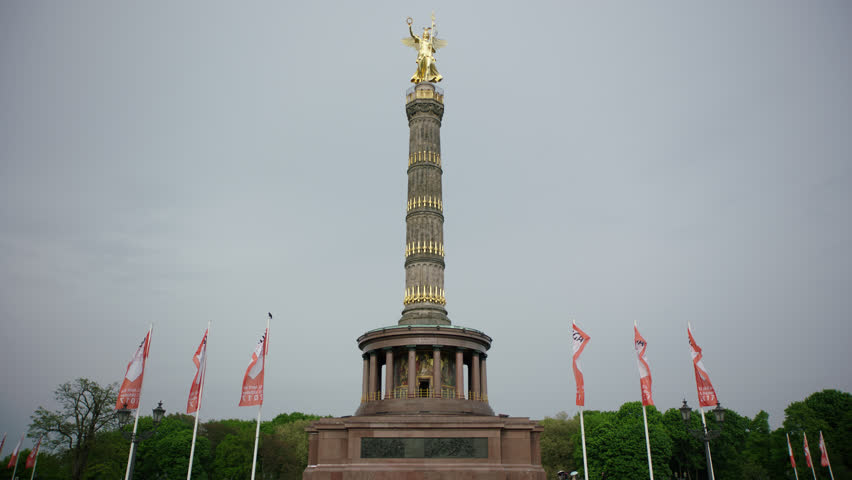 May, 2017 Berlin, Germany. Victory Column low wide angle looking up with flags on a cloudy day.