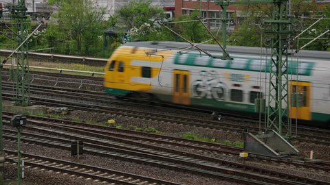 May, 2017 Berlin, Germany. Fast moving regional train passes by at the Harbor train yard on a cloudy day.